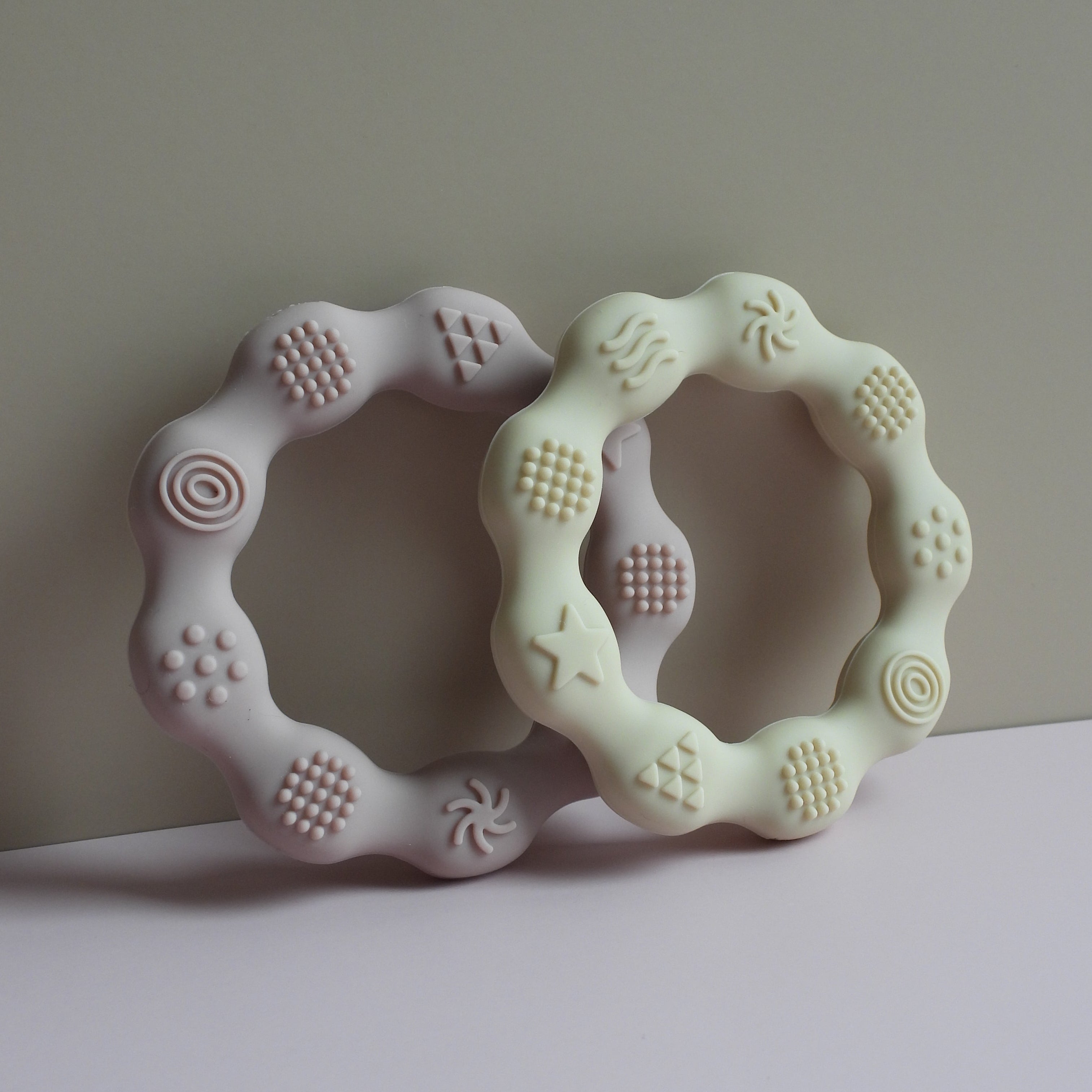 Two light green teething rings on a plain background